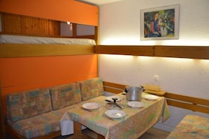 A room with bunk beds, a sofa, and a dining table set with plates and a kettle.