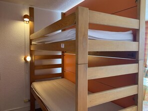 A bunk bed with a wooden frame and white bedding. - 10m from ski slopes, 3rd floor, view ski slopes, balcony, tv, 24m², Les Menuires (Les Menuires)