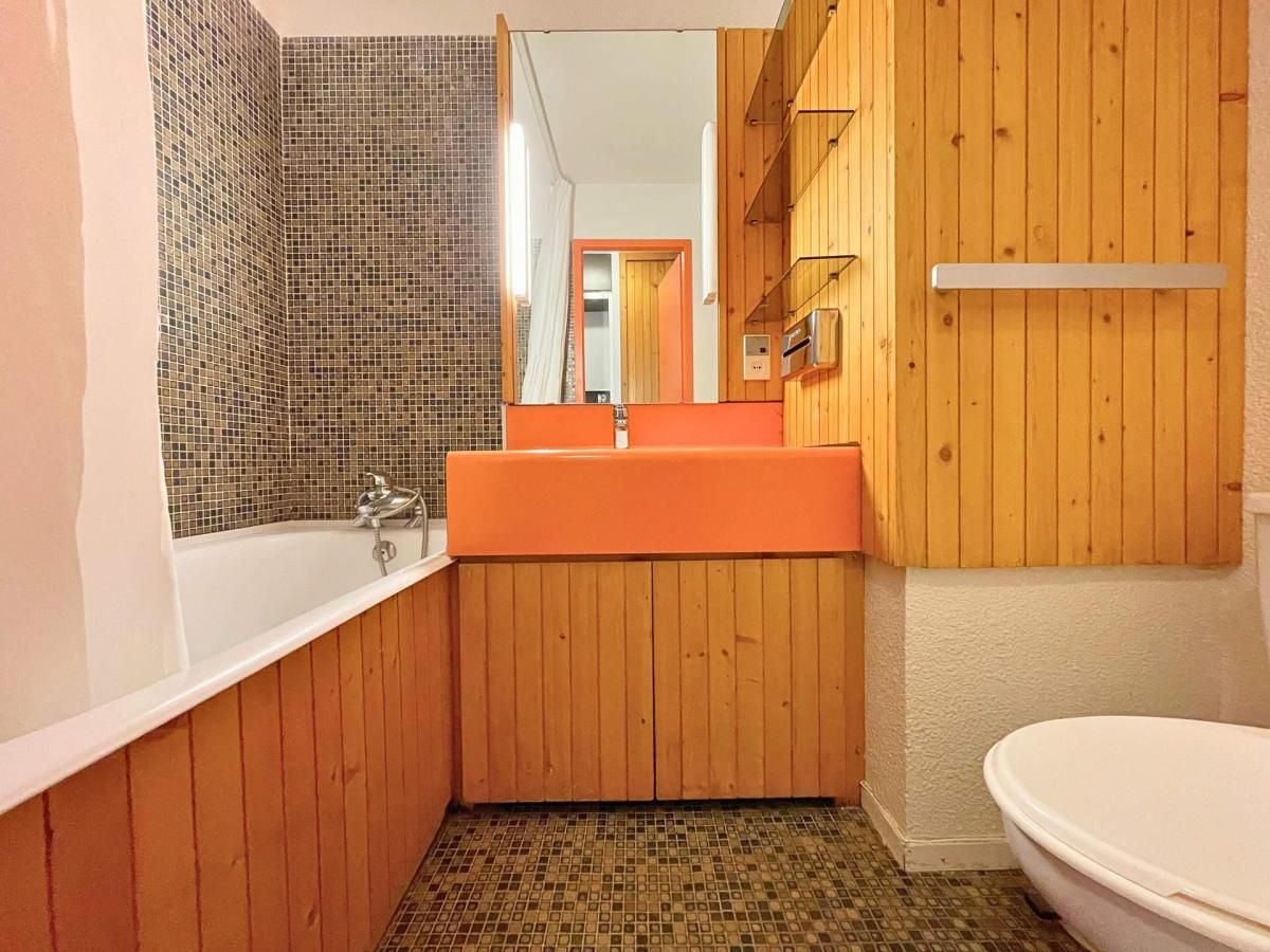 A bathroom with a wooden vanity, a bathtub, and a toilet.