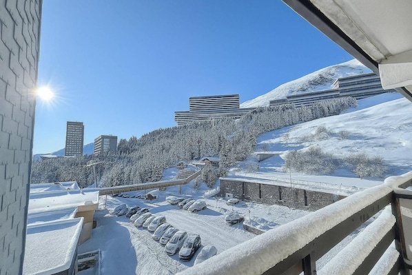 A snowy landscape with a parking lot, buildings, and a clear sky.