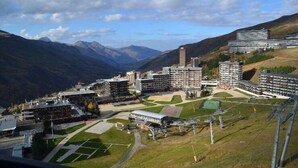 Ein Hotelkomplex mit mehreren Gebäuden, einem Sportplatz und dahinter Berglandschaft.