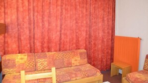 A room with a patterned sofa, a small wooden table, and an orange radiator.
