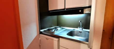 A compact kitchen with a sink, stove, and cabinets.