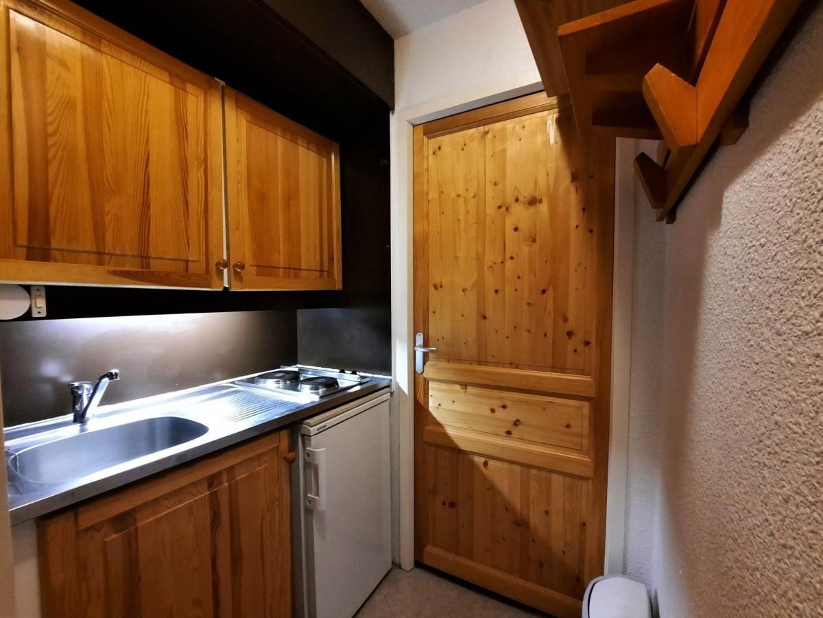 A compact kitchen with wooden cabinets, a stainless steel sink, and a built-in dishwasher.