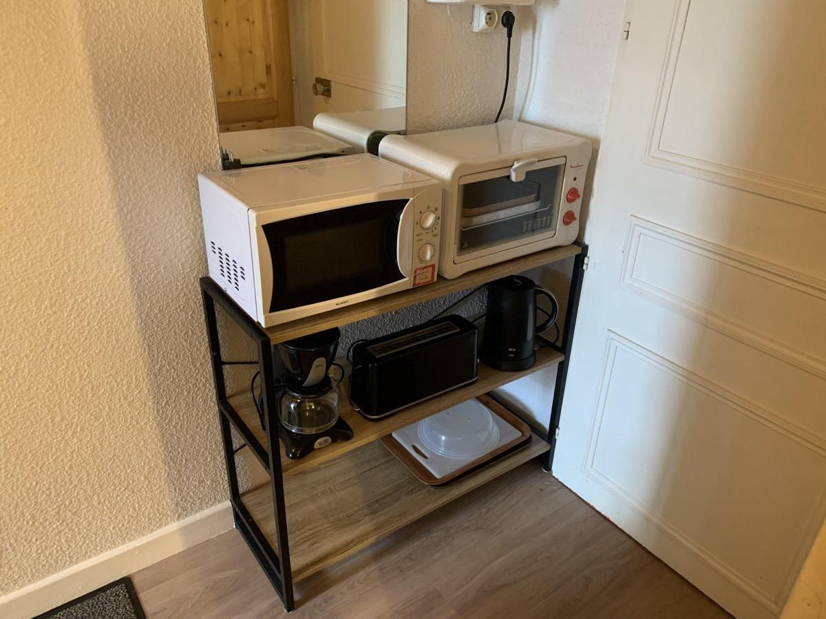 A kitchenette with a microwave, toaster, coffee maker, and a small oven on a black metal stand.