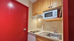 A compact kitchen with wooden cabinets, a microwave, a sink, and a dishwasher. - 10m from ski slopes, 7th floor, balcony, tv, 22m², Les Menuires (Les Menuires)