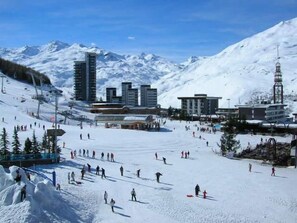 A ski resort with multiple buildings, ski slopes, and a mountainous backdrop.