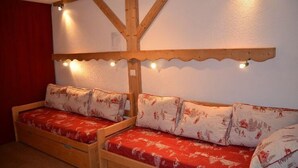A cozy room with two wooden bunk beds, each with a red and white patterned mattress and matching pillows. - 10m from ski slopes, 7th floor, balcony, tv, 22m², Les Menuires (Les Menuires)