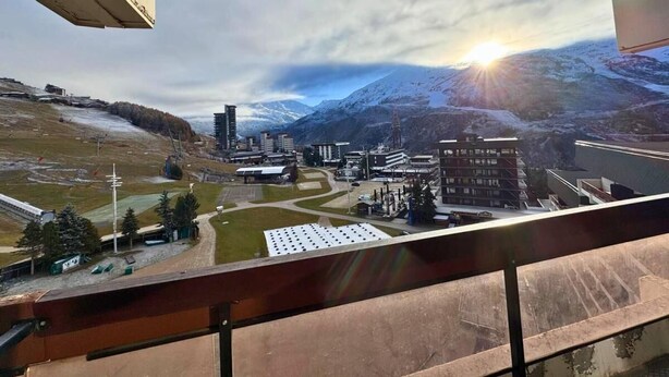 A view from a balcony overlooking a ski resort with buildings, a ski lift, and a mountain backdrop. - 10m from ski slopes, 7th floor, balcony, tv, 22m², Les Menuires (Les Menuires)