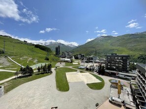 A ski resort with a parking area, buildings, and a mountainous backdrop.