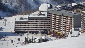 A multi-story hotel with balconies, ski lift access, and a snowy mountain backdrop. - 10m from ski slopes, 7th floor, balcony, tv, 22m², Les Menuires (Les Menuires)