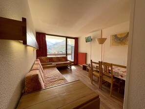 A compact living space with a sofa set, a dining table with chairs, and a view through a large window. - 10m from ski slopes, 7th floor, balcony, tv, 36m², Les Menuires (Les Menuires)