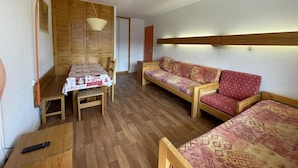 A small, cozy room with a wooden table, two sofas, and a TV mounted on the wall. - 10m from ski slopes, 7th floor, balcony, tv, 36m², Les Menuires (Les Menuires)