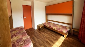 A room with two bunk beds, a small wooden table, and a door. - 10m from ski slopes, 7th floor, balcony, tv, 36m², Les Menuires (Les Menuires)