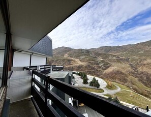 A balcony with a view of a mountainous landscape, a building with a modern design, and a paved area with a few trees. - 10m from ski slopes, 8th floor, balcony, tv, 18m², Les Menuires (Les Menuires)