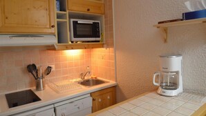 A compact kitchen with wooden cabinets, a microwave, a coffee maker, and a sink. - 10m from ski slopes, 6th floor, balcony, tv, 55m², Les Menuires (Les Menuires)