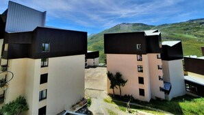 A modern building with a flat roof and a flat facade, surrounded by a parking area and greenery. - 300m from resort center, 3rd floor, view mountain, balcony, tv, ski locker, 20m², Les Menuires (Les Menuires)