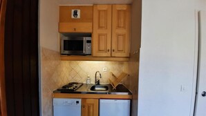 A compact kitchen with wooden cabinets, a microwave, a sink, and a dishwasher. - 300m from resort center, 3rd floor, view mountain, balcony, tv, ski locker, 20m², Les Menuires (Les Menuires)