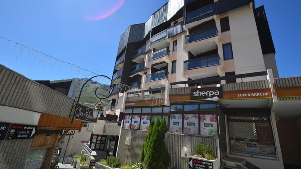 A multi-story building with commercial establishments on the ground floor, including a supermarket and a restaurant. - 10m from ski slopes, 7th floor, balcony, tv, ski locker, 28m², Les Menuires (Les Menuires)