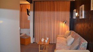 A cozy room with a wooden bed, a small table with cups and a pitcher, and a floral sofa. - 10m from ski slopes, 7th floor, balcony, tv, ski locker, 28m², Les Menuires (Les Menuires)