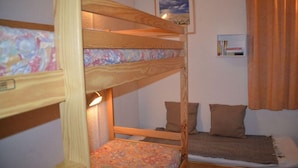 A bunk bed room with a wooden frame, a lower bunk with a floral bedspread, and an upper bunk with a brown pillow. - 10m from ski slopes, 7th floor, balcony, tv, ski locker, 28m², Les Menuires (Les Menuires)