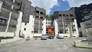 A multi-story residential building with balconies, a central entrance, and a parking area. - 10m from ski slopes, 1st floor, tv, ski locker, 25m², Les Menuires (Les Menuires)