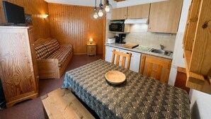 A compact room with a bed, a small table, a microwave, a sink, and wooden cabinets. - 10m from ski slopes, 1st floor, tv, ski locker, 25m², Les Menuires (Les Menuires)
