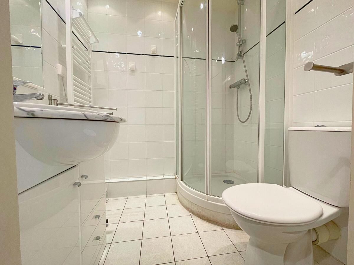 A modern bathroom with a glass-enclosed shower, a white toilet, and a vanity with a mirror and sink.