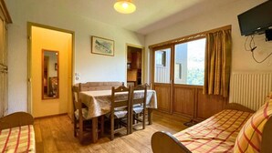 A cozy room with a wooden dining table, two wooden chairs, a sofa, and a television mounted on the wall. - 10m from ski slopes, Ground floor, balcony, tv, ski locker, 31m², Les Menuires (Les Menuires)