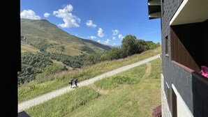 A view from a window overlooking a dirt path leading through a hilly landscape. - 10m from ski slopes, Ground floor, balcony, tv, ski locker, 31m², Les Menuires (Les Menuires)