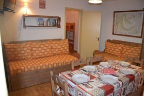 Um quarto acolhedor com sofá e uma mesa de jantar posta para quatro pessoas.