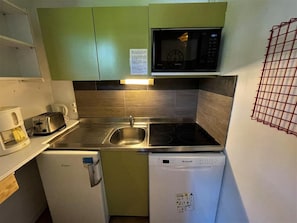 A compact kitchen with a microwave, toaster, sink, and dishwasher.