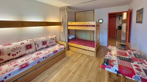 Una habitación pequeña con una litera, un sofá y una mesita.
