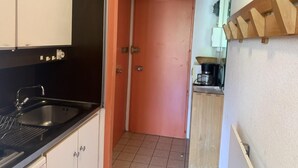 Una cocina con encimera negra, pileta de acero inoxidable y muebles blancos.