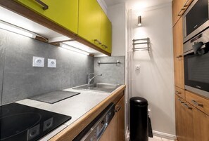 A modern kitchen with a built-in stove, a sink, and wooden cabinets. - 10m from ski slopes, 4th floor, balcony, tv, ski locker, 31m², Les Menuires (Les Menuires)