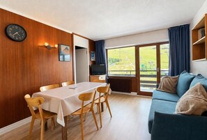 A room with a dining table, chairs, a sofa, a TV, and a large window with a view. - 10m from ski slopes, 4th floor, balcony, tv, ski locker, 31m², Les Menuires (Les Menuires)