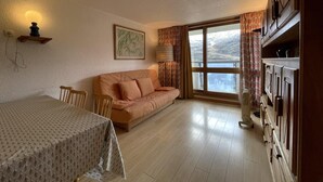 A room with a dining table, sofa, and a large window with curtains. - 200m from shops, 2nd floor, balcony, tv, ski locker, 44m², Les Menuires (Les Menuires)