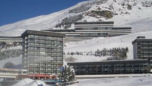 A modern hotel with multiple floors, large windows, and a ski slope in the background. - 10m from ski slopes, 10th floor, balcony, tv, ski locker, 48m², Les Menuires (Les Menuires)