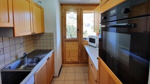 A compact kitchen with wooden cabinets, a stainless steel sink, a microwave, and a black oven. - 10m from ski slopes, 10th floor, balcony, tv, ski locker, 48m², Les Menuires (Les Menuires)
