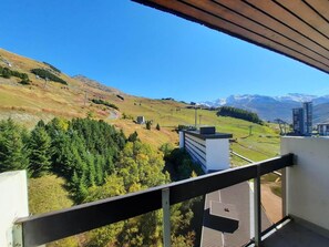 A balcony with a view of a mountainous landscape, a building with a flat roof, and a clear sky. - 10m from ski slopes, 10th floor, balcony, tv, ski locker, 48m², Les Menuires (Les Menuires)