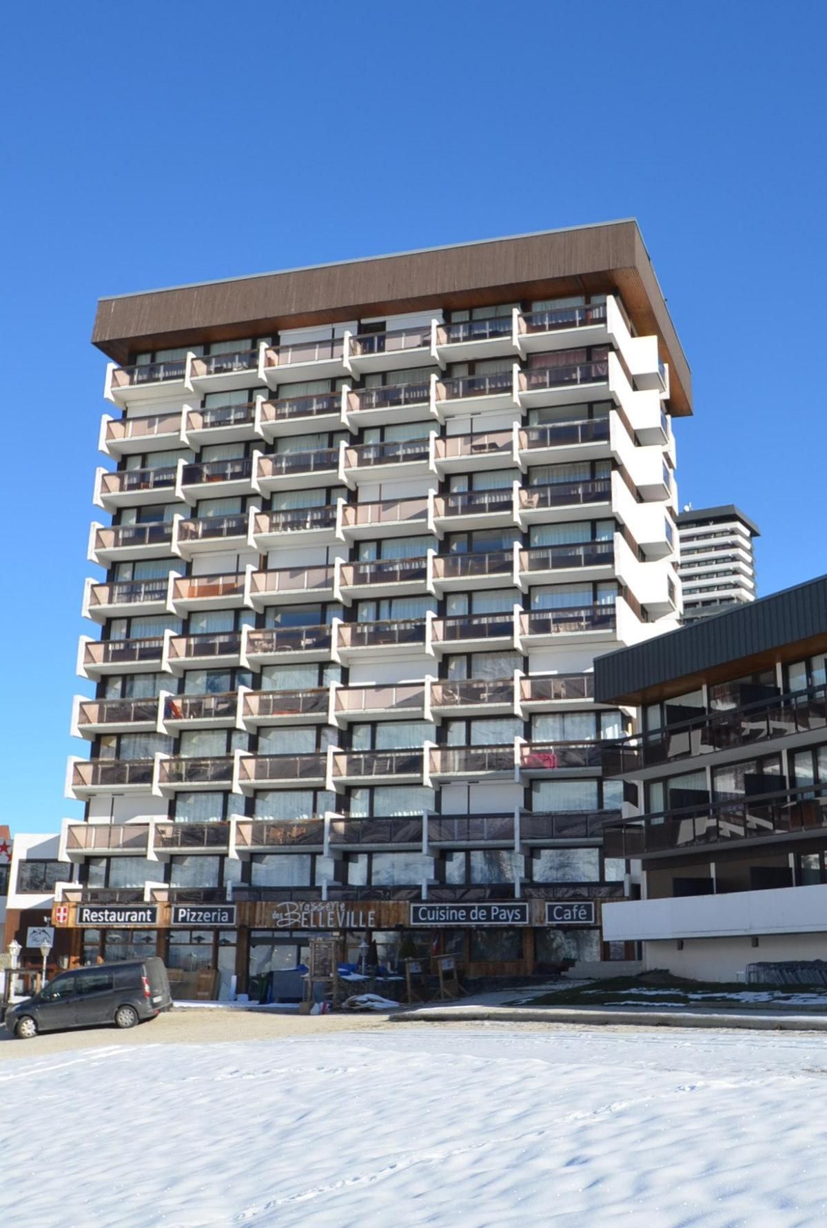 Un hotel de varios pisos con balcones, un restaurante y una pizzería en la planta baja.