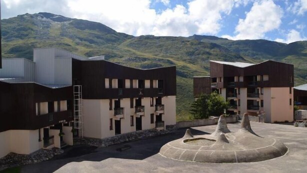 Un edificio moderno con numerosi balconi e un cortile centrale arricchito da elementi scultorei.