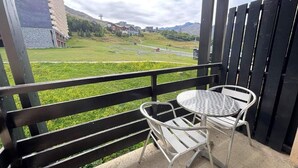 A balcony with a metal table and chairs, overlooking a green landscape and buildings in the distance. - 150m from shops, 3rd floor, view ski slopes, balcony, tv, ski locker, 26m², Les Menuires (Les Menuires)