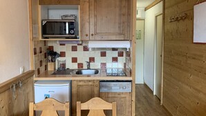 Une cuisine compacte avec des meubles en bois, un four à micro-ondes, un évier et un lave-vaisselle.