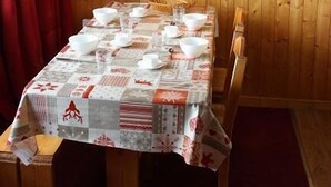 Une pièce aux murs lambrés, avec une table dressée pour le repas, une machine à café et une étagère sur laquelle se trouve une tasse.