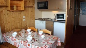 Une cuisine compacte avec des murs en bois, un four à micro-ondes, une cuisinière et un lave-vaisselle.