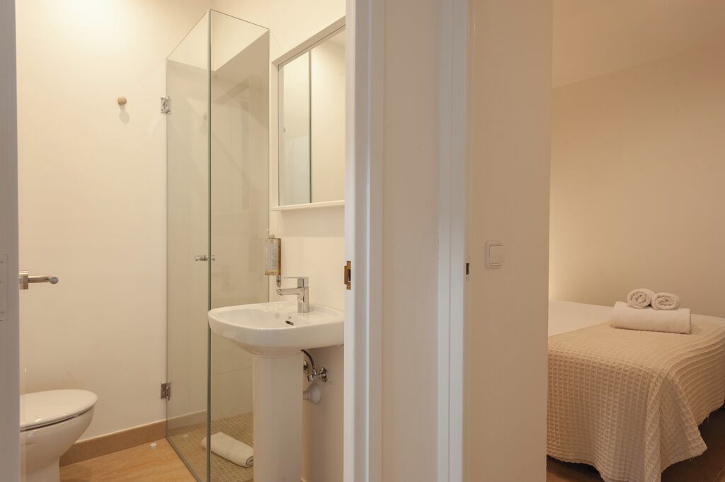 A bathroom with a glass shower enclosure, a white sink, and a toilet.