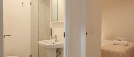A bathroom with a glass shower enclosure, a white sink, and a toilet.