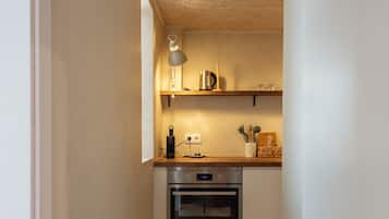 Una cocina estrecha con armarios blancos, una encimera de madera y una lámpara colgante.