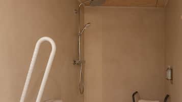 Un baño pequeño individual con inodoro, ducha y un banco accesible en silla de ruedas.